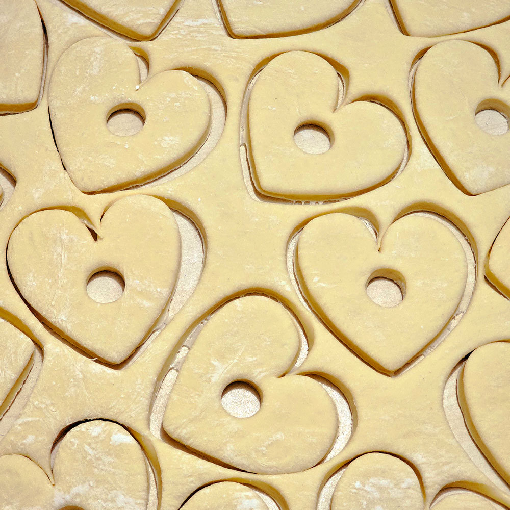 Heart shapes cut into a sheet of pale dough
