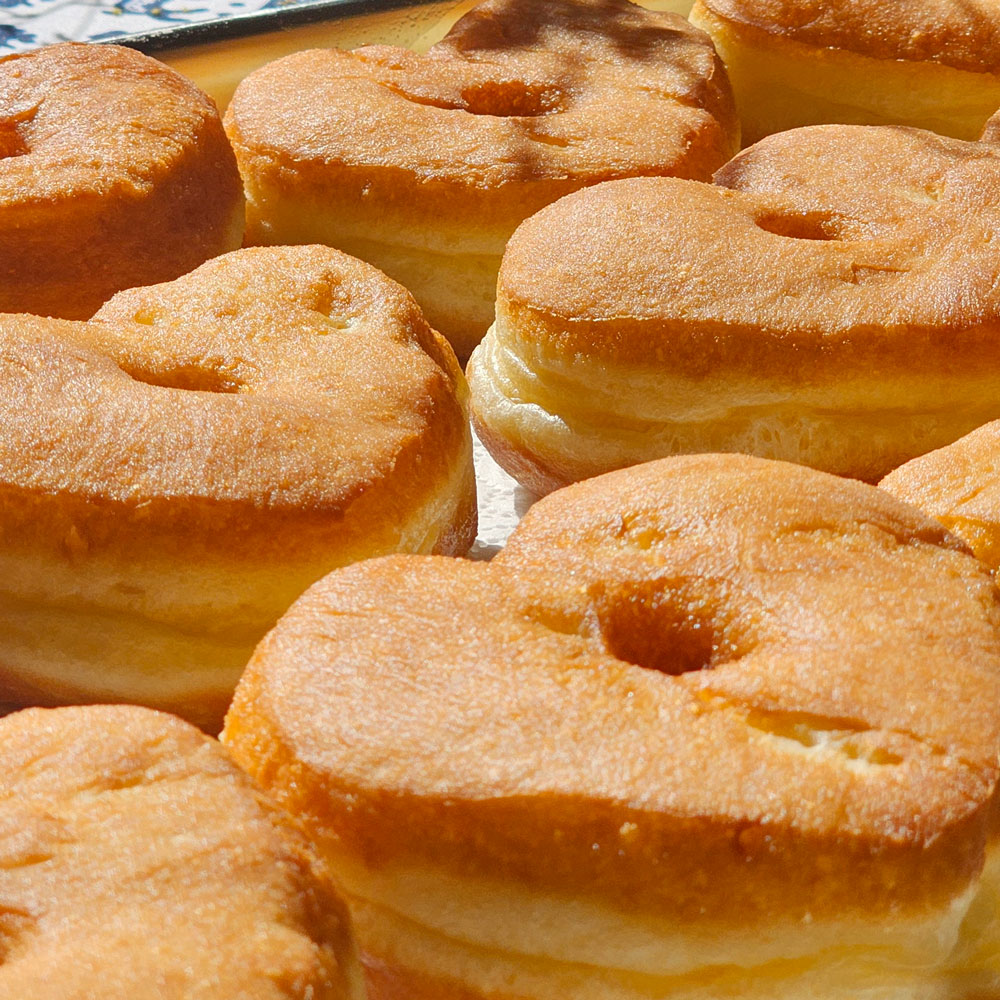Puffed golden heart donuts stacked after frying