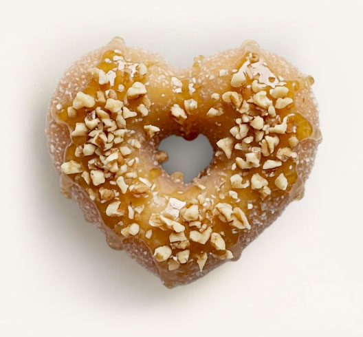 Finished honey heart donut topped with crushed walnuts